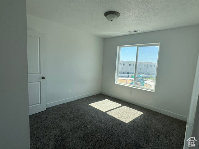 Carpeted spare room with a textured ceiling and baseboards