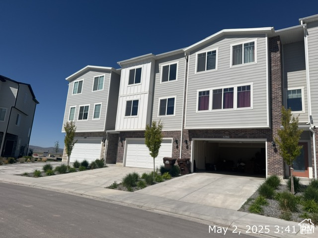 Multi unit property featuring an attached garage, concrete driveway, and brick siding