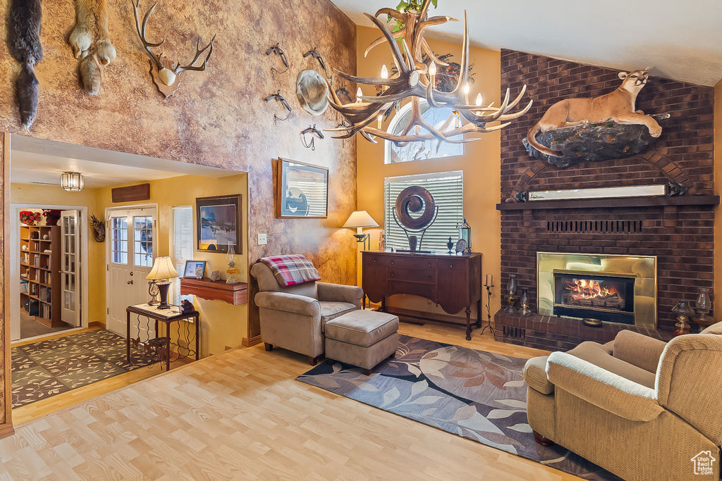 Living room with wood finished floors, a fireplace, a chandelier, and high vaulted ceiling