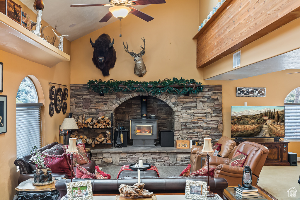 Carpeted living area with ceiling fan, a wood stove, and vaulted ceiling