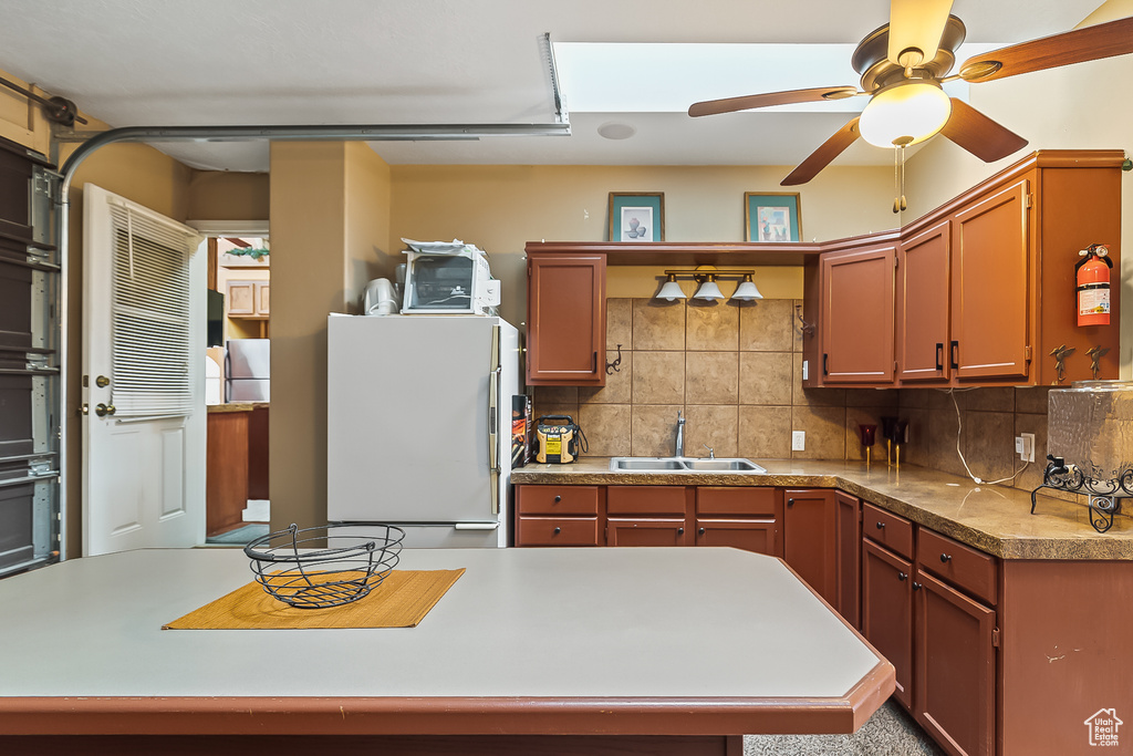 Kitchen featuring freestanding refrigerator, a sink, decorative backsplash, and ceiling fan