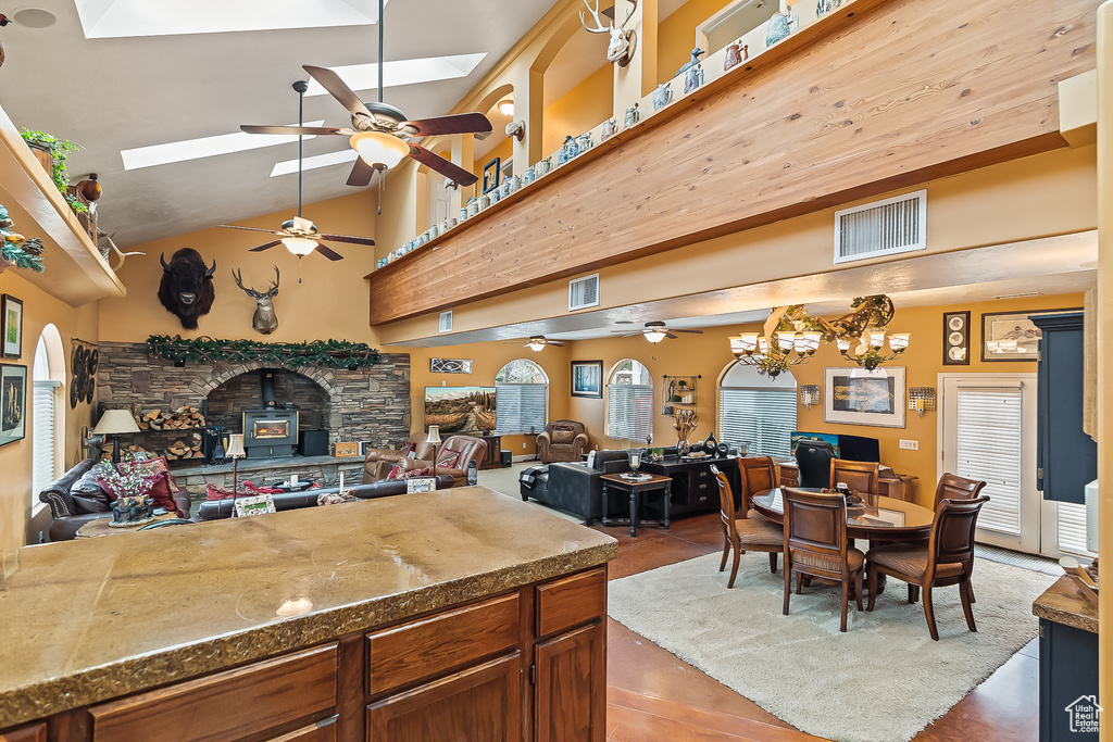 Kitchen featuring a skylight, a ceiling fan, open floor plan, plenty of natural light, and high vaulted ceiling