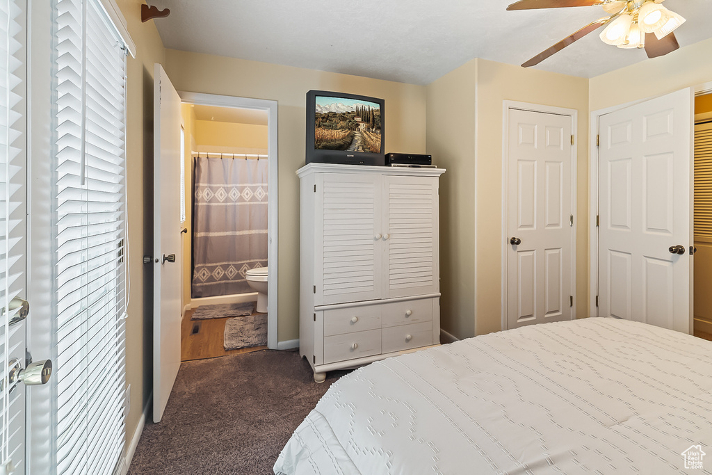 Bedroom with carpet, ensuite bathroom, ceiling fan, and baseboards