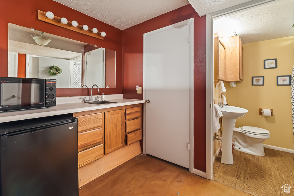 Bathroom with a sink, a textured ceiling, toilet, and baseboards
