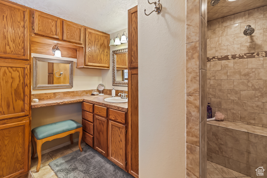 Bathroom with a stall shower, tile patterned floors, vanity, and a textured ceiling