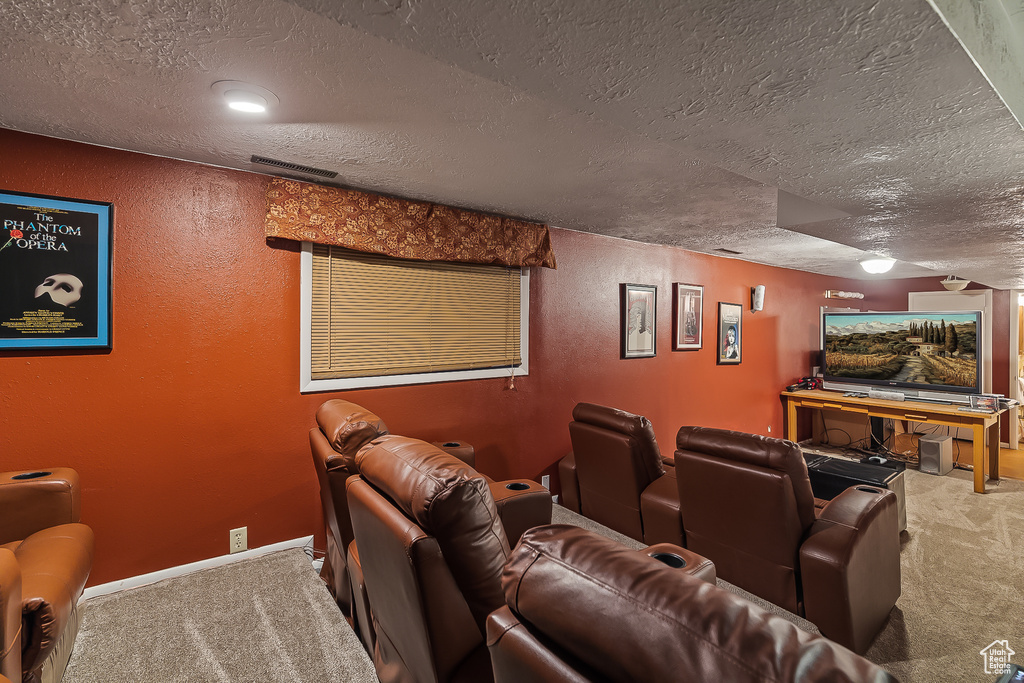 Cinema room featuring carpet floors, a textured ceiling, a textured wall, and baseboards