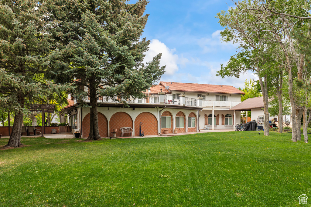 Rear view of house featuring a balcony, a lawn, and a pergola