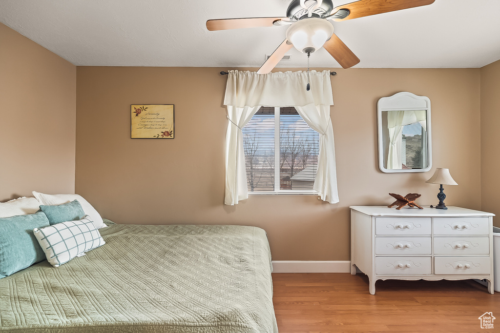 Bedroom with light wood-style floors, baseboards, and a ceiling fan