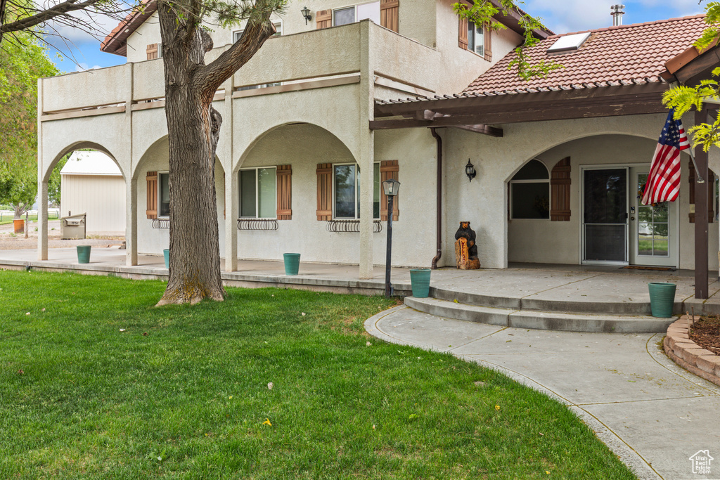 Back of property featuring stucco siding, a yard, a patio, and a balcony