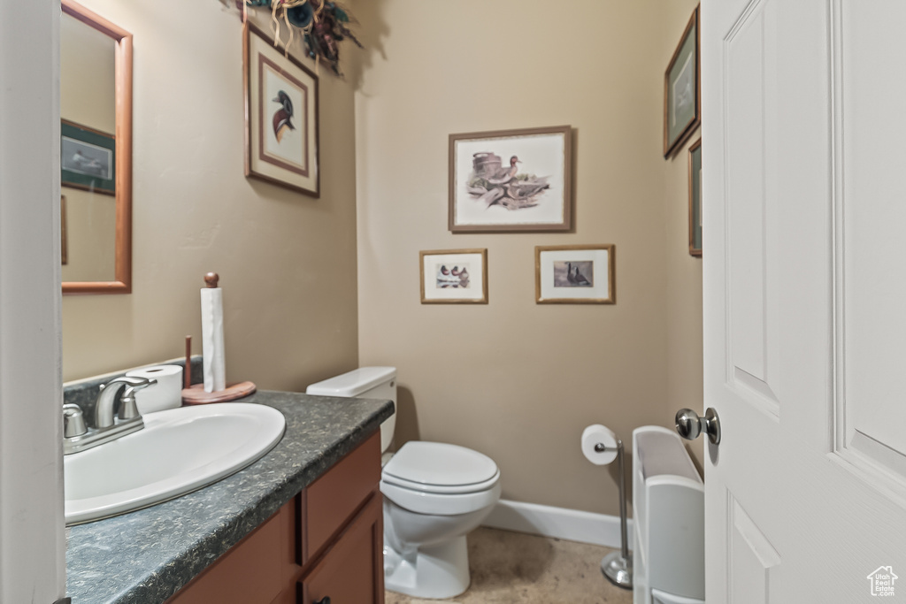 Half bathroom featuring toilet, vanity, and baseboards