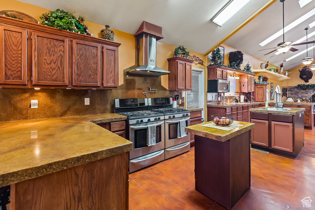 Kitchen featuring an island with sink, appliances with stainless steel finishes, wall chimney exhaust hood, a sink, and tasteful backsplash