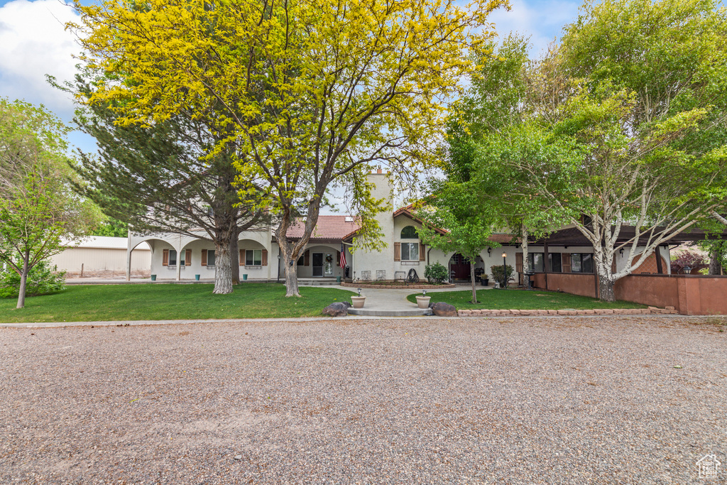 View of front of house featuring stucco siding, a front lawn, and a chimney