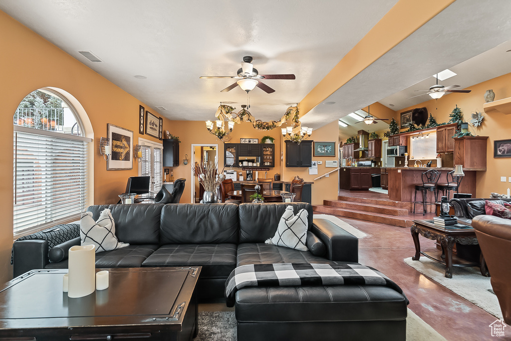 Living room featuring ceiling fan, a chandelier, and finished concrete flooring