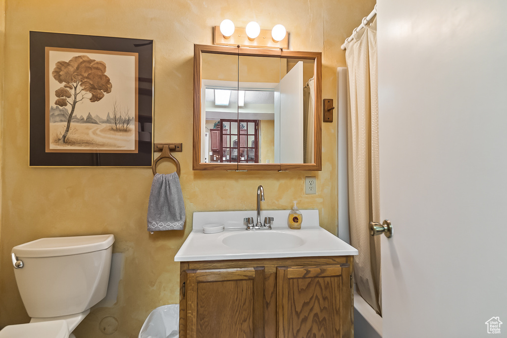 Bathroom featuring toilet, vanity, and a shower with curtain