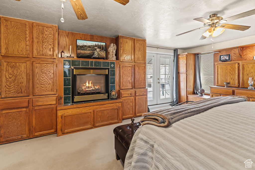 Bedroom with carpet floors, access to exterior, a tiled fireplace, and ceiling fan