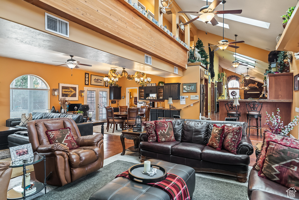Living room featuring ceiling fan, a chandelier, and a skylight