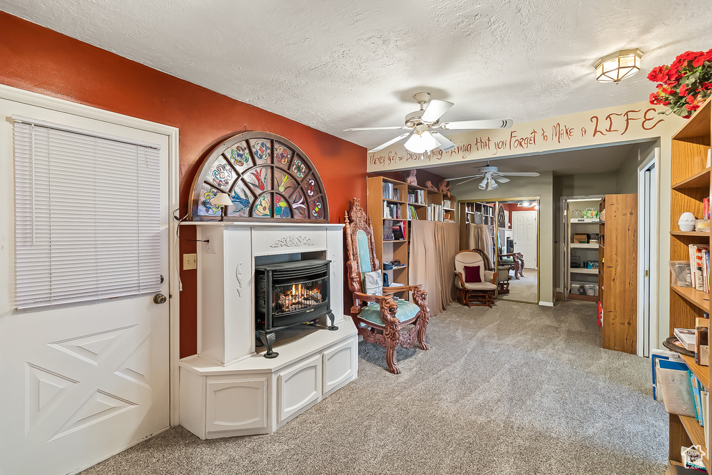 Living area with ceiling fan, carpet flooring, and a textured ceiling