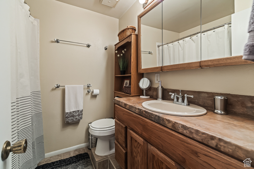 Full bath with toilet, vanity, baseboards, and tile patterned flooring