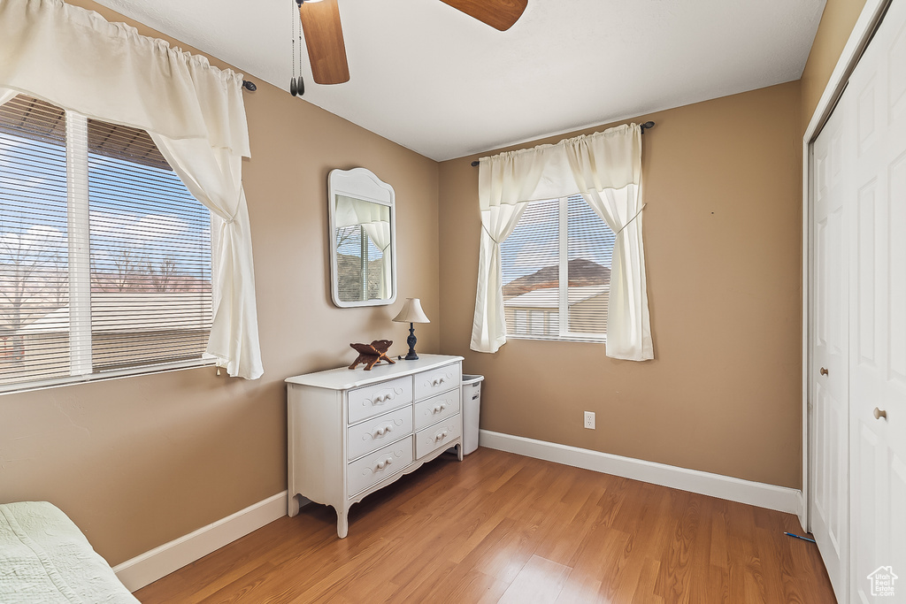 Bedroom with a closet, baseboards, light wood-style flooring, and ceiling fan