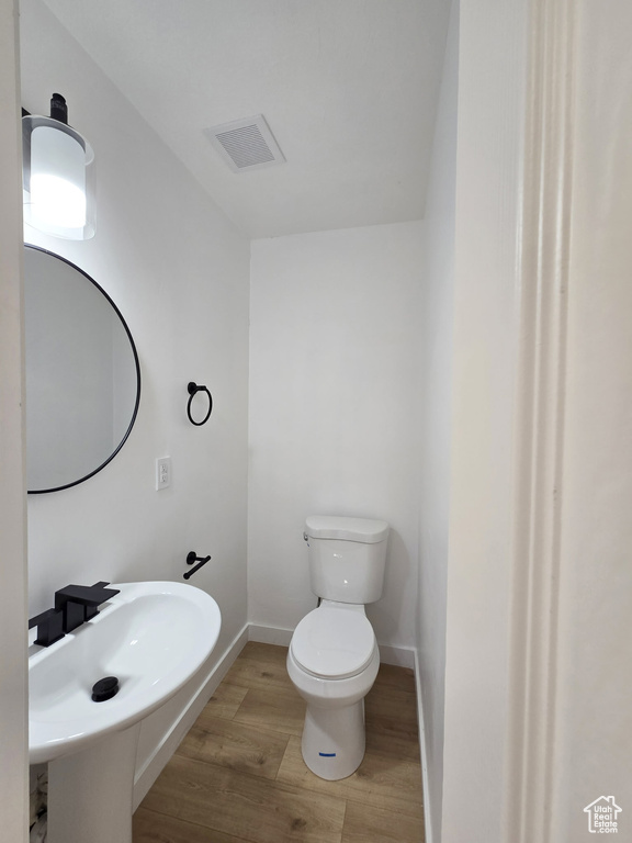 Half bathroom with wood finished floors, toilet, baseboards, and a sink