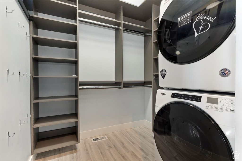 Laundry area with stacked washer / dryer, wood finished floors, and baseboards