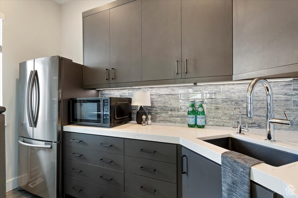Kitchen featuring gray cabinets, black microwave, a sink, tasteful backsplash, and modern cabinets