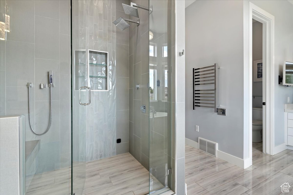 Bathroom featuring radiator, toilet, a shower stall, baseboards, and a towel warmer