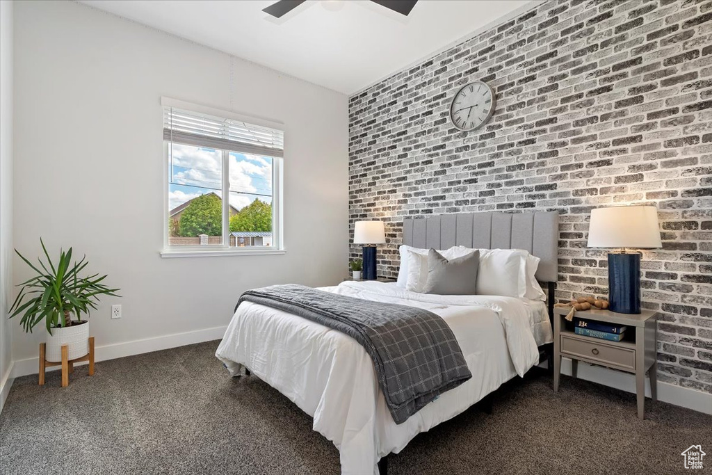 Bedroom with baseboards, carpet flooring, brick wall, and ceiling fan