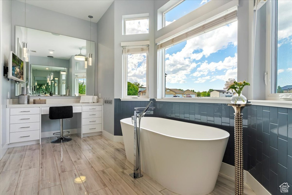 Full bathroom with a freestanding tub, wood finished floors, baseboards, and vanity
