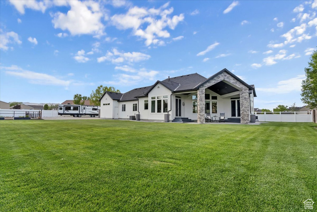Back of property featuring stone siding, a patio, and stucco siding