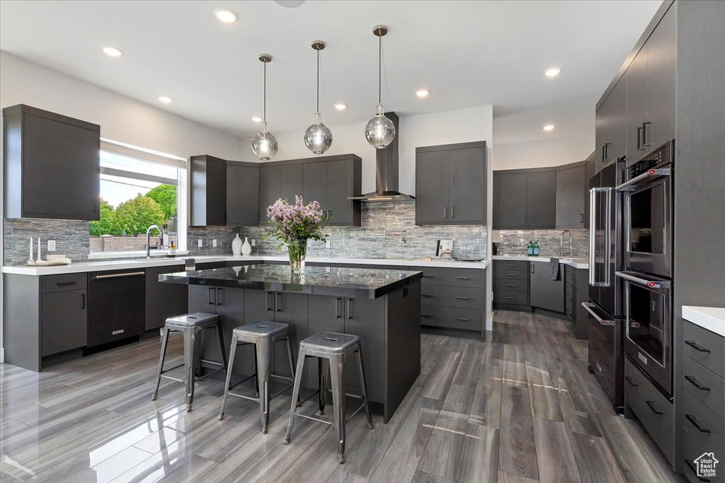 Kitchen with appliances with stainless steel finishes, a kitchen island, a breakfast bar, backsplash, and recessed lighting