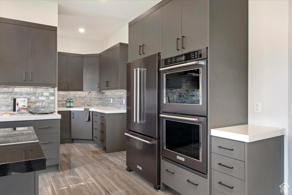 Kitchen featuring stainless steel appliances, gray cabinets, decorative backsplash, light countertops, and recessed lighting