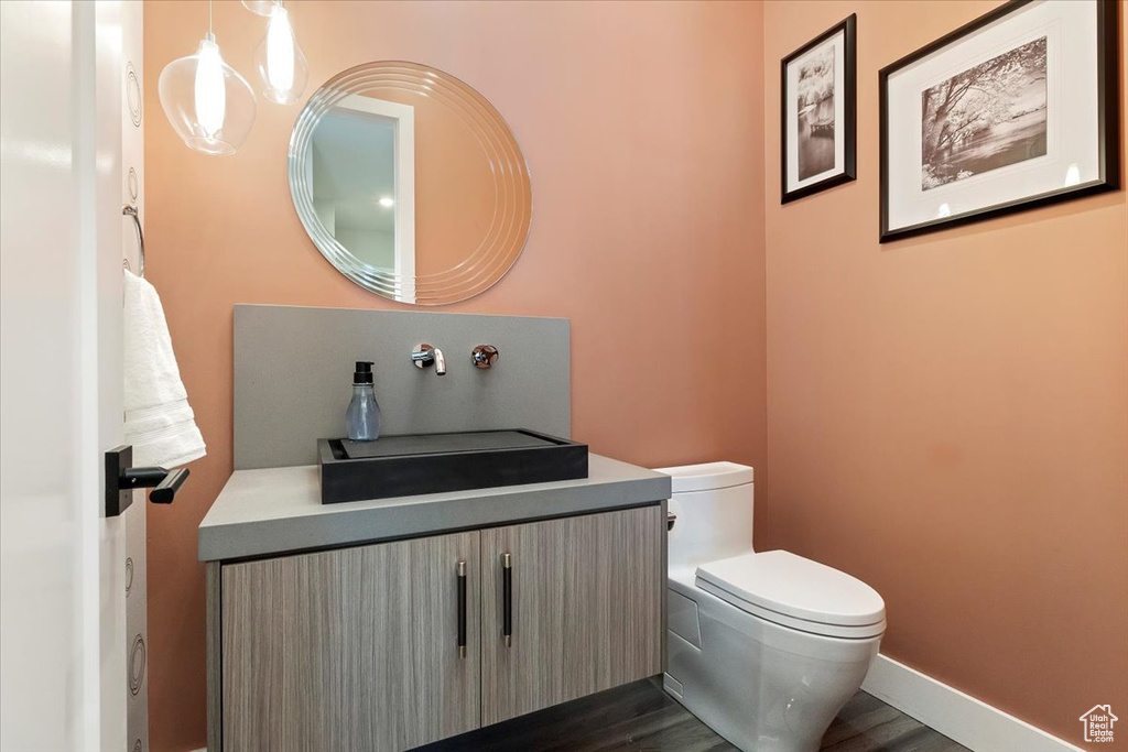 Half bath featuring toilet, vanity, and wood finished floors