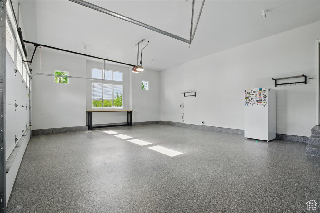 Garage featuring freestanding refrigerator, a garage door opener, and baseboards