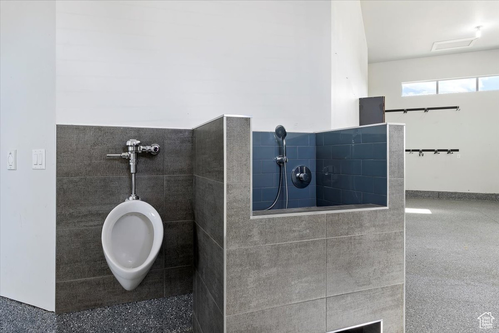 Full bathroom with tiled shower and speckled floor