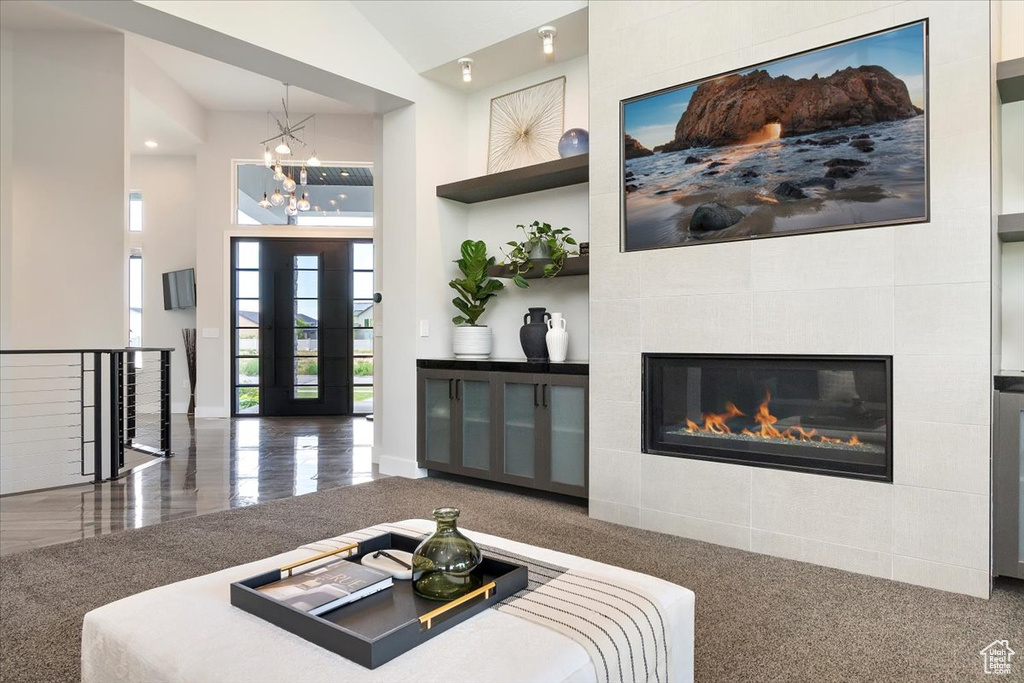 Living area with a towering ceiling, a chandelier, a fireplace, and baseboards
