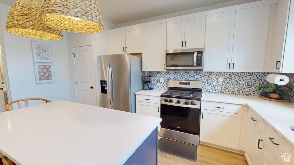 Kitchen with stainless steel appliances, light countertops, tasteful backsplash, a center island, and light wood-style floors