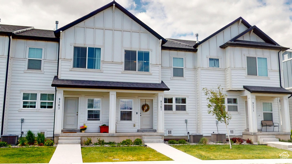 Multi unit property featuring board and batten siding, central AC unit, covered porch, and a front lawn