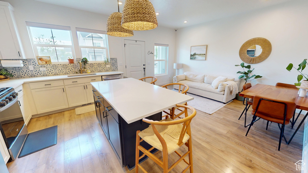Kitchen featuring a breakfast bar, light countertops, a center island, backsplash, and recessed lighting
