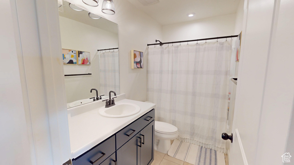 Bathroom with tile patterned floors, toilet, vanity, and a shower with shower curtain