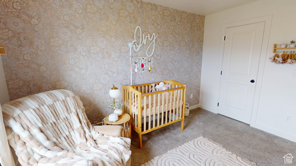Carpeted bedroom with a crib and baseboards
