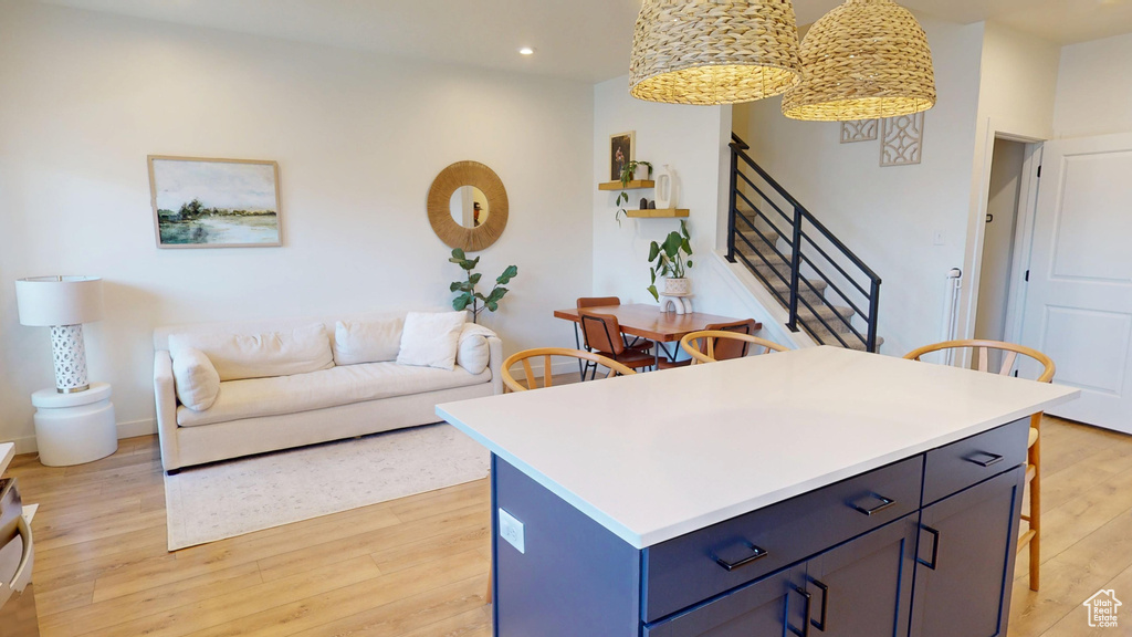 Kitchen with light wood-type flooring, recessed lighting, a breakfast bar area, light countertops, and open floor plan