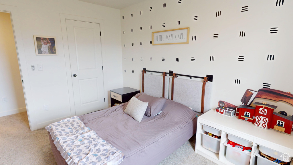 Bedroom with light colored carpet, a closet, and baseboards
