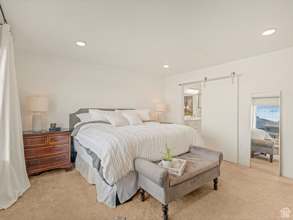 Bedroom with light carpet, a barn door, recessed lighting, and connected bathroom
