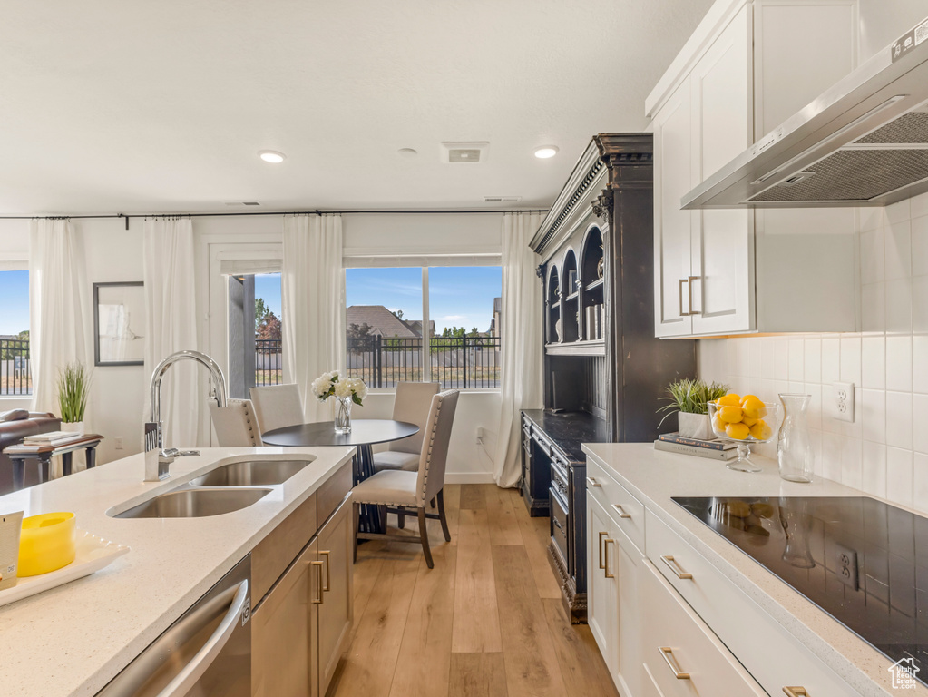 Kitchen with extractor fan, a sink, black electric stovetop, light wood finished floors, and recessed lighting