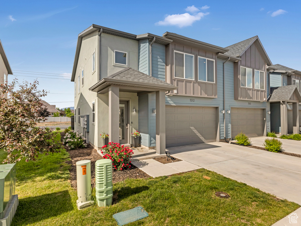 View of front of home featuring an attached garage, board and batten siding, concrete driveway, and a front lawn