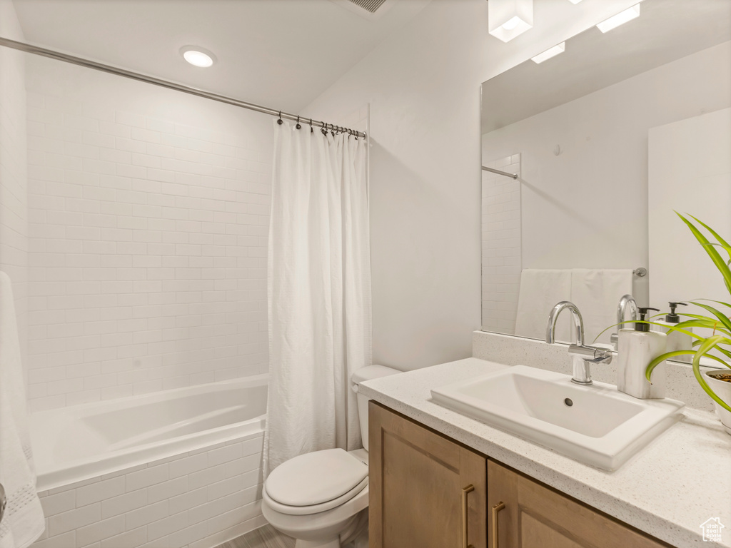 Bathroom with toilet, tiled shower / bath, and vanity