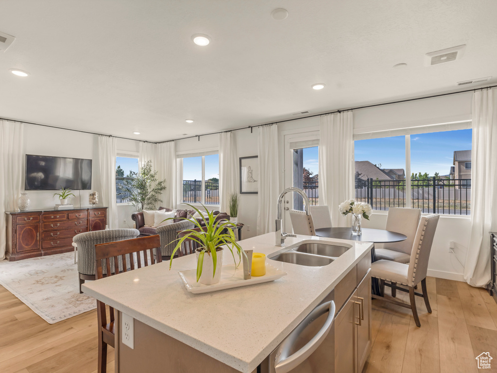 Kitchen featuring a sink, dishwasher, light wood finished floors, recessed lighting, and open floor plan