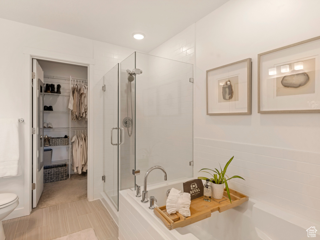 Bathroom featuring a shower stall, a garden tub, a spacious closet, and toilet