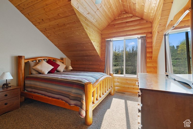 Carpeted bedroom featuring wooden ceiling, lofted ceiling, multiple windows, and rustic walls